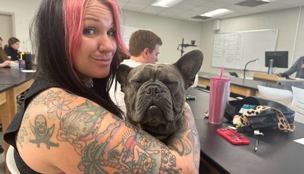 Adoptable dog Vinny in woman's lap at college lecture